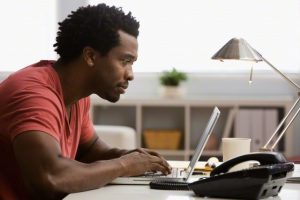 Serious Black man working on laptop in home office